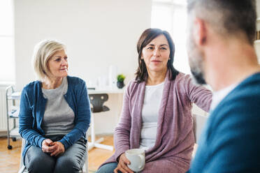 Seriöse Männer und Frauen, die während einer Gruppentherapie im Kreis sitzen und sich gegenseitig unterstützen. - HPIF23343