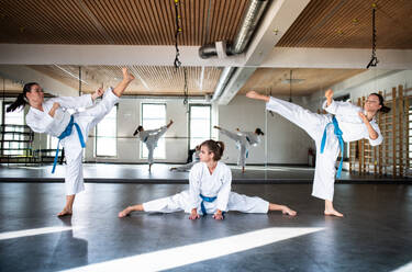 A group of young women practising karate indoors in gym. - HPIF23355