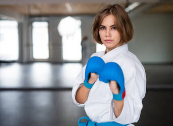 Eine attraktive junge Frau, die drinnen in einer Turnhalle Karate übt. - HPIF23359