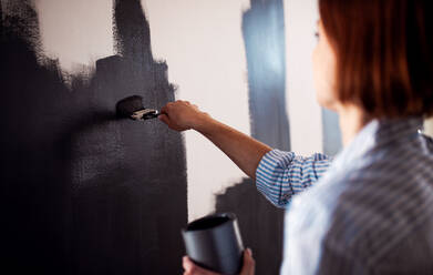 A young creative woman painting wall black. A startup of small business. - HPIF23366