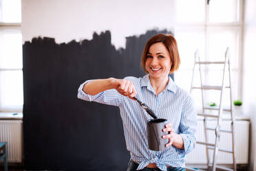 A portrait of young creative woman painting wall black. A startup of small business. - HPIF23372