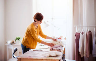 Junge kreative Frau bei der Arbeit in einem Atelier, Gründung eines kleinen Schneidereibetriebs. - HPIF23389