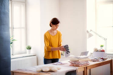 Junge kreative Frau bei der Arbeit in einem Atelier, Gründung eines kleinen Schneidereibetriebs. - HPIF23390