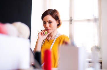 Junge, kreative Frau in einem Atelier bei der Arbeit, Start eines kleinen Schneidereibetriebs. - HPIF23407