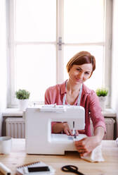 Young creative woman in a studio, working. A startup of small tailoring business. - HPIF23426