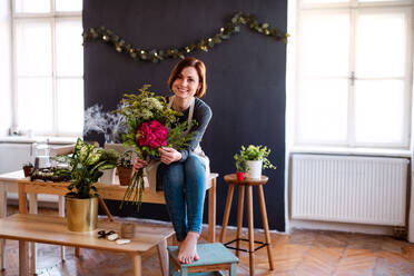 Eine junge, kreative Frau, die in einem Blumenladen Blumen arrangiert, eine Neugründung eines Blumenladens. - HPIF23457