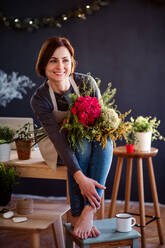 Eine junge, kreative Frau, die in einem Blumenladen Blumen arrangiert, eine Neugründung eines Blumenladens. - HPIF23458