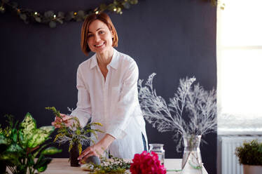 Eine junge, kreative Frau, die in einem Blumenladen Blumen arrangiert, eine Neugründung eines Blumenladens. - HPIF23467