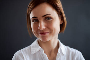 A close-up portrait of young beautiful woman standing against dark background. - HPIF23474