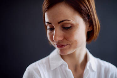 A close-up portrait of young beautiful woman standing against dark background. - HPIF23475