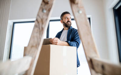 Ein reifer Mann mit Tablet und Kartons, der ein neues Haus einrichtet. Ein neues Hauskonzept. - HPIF23480