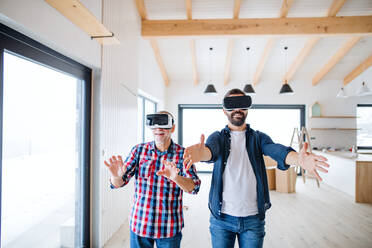 A mature man with VR goggles and his senior father furnishing new house, a new home concept. - HPIF23494