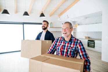 Ein fröhlicher älterer Mann, der seinem reifen Sohn bei der Einrichtung eines neuen Hauses hilft, ein neues Wohnkonzept. - HPIF23503