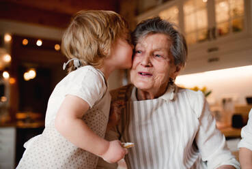 Glückliche ältere Urgroßmutter mit kleinem Kleinkind, das zu Hause Kuchen backt und sich küsst. - HPIF23571