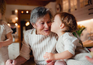 Glückliche ältere Urgroßmutter mit kleinen Kleinkindern, die zu Hause Kuchen backen. - HPIF23572