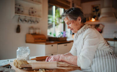 Eine ältere Frau, die zu Hause in einer Küche Kuchen backt. Kopierraum. - HPIF23598