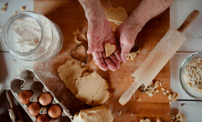 A midsection of old woman making cakes in a kitchen at home. Top view. - HPIF23600