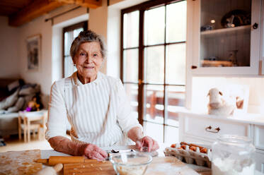 Eine ältere Frau, die zu Hause in einer Küche Kuchen backt. Kopierraum. - HPIF23606
