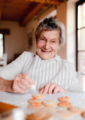 Eine ältere Frau backt und dekoriert Kuchen in einer Küche zu Hause. - HPIF23627