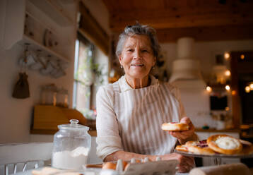 Eine ältere Frau, die zu Hause in einer Küche Kuchen backt. Kopierraum. - HPIF23631