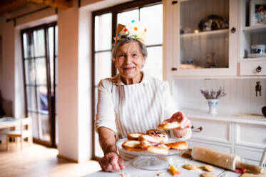 Eine ältere Frau, die zu Hause in einer Küche Kuchen backt. Kopierraum. - HPIF23634