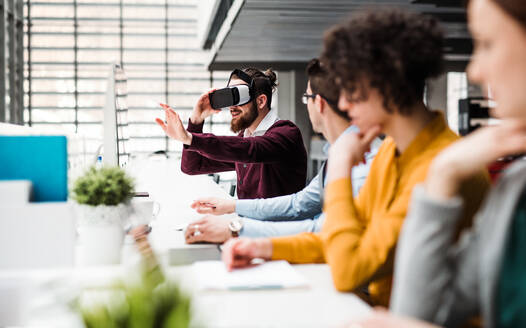 Eine Gruppe junger Geschäftsleute mit Computern und VR-Brillen, die im Büro zusammenarbeiten. Kopierraum. - HPIF23639