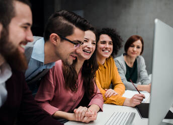 Eine Gruppe von jungen Geschäftsleuten, die im Büro zusammenarbeiten und sich unterhalten. - HPIF23643