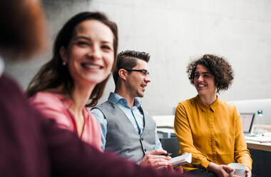 A group of young businesspeople working together in office, talking. - HPIF23648