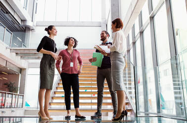 A group of young businesspeople standing near a staircase, talking. - HPIF23699