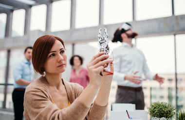 A young businesswoman or scientist with robotic hand standing in office, working. - HPIF23720