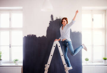 A portrait of young creative woman painting wall black. A startup of small business. - HPIF23734