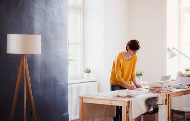 Junge kreative Frau mit Laptop, die in einem Atelier arbeitet, Gründung eines kleinen Schneidereibetriebs. - HPIF23735