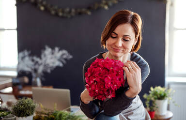 Ein Porträt einer jungen, kreativen Frau, die in einem Blumenladen Blumen arrangiert und ein Blumengeschäft eröffnet. - HPIF23754