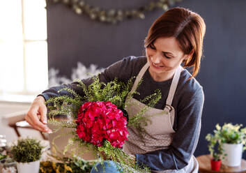 A young creative woman arranging flowers in a flower shop. A startup of florist business. - HPIF23755