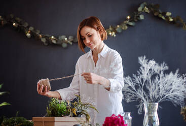 Eine junge, kreative Frau, die in einem Blumenladen Blumen arrangiert, eine Neugründung eines Blumenladens. - HPIF23763