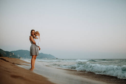 A young mother with a toddler girl on beach on summer holiday. Copy space. - HPIF23775