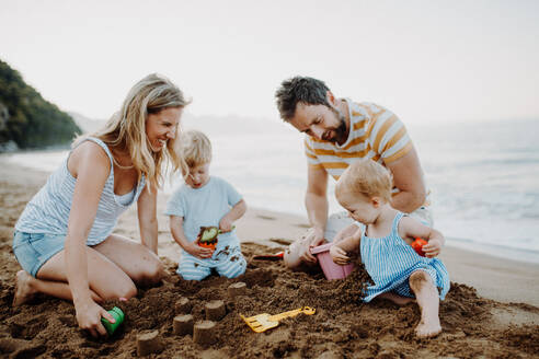 Eine junge Familie mit Kleinkindern spielt im Sommerurlaub am Strand mit Sand. - HPIF23782