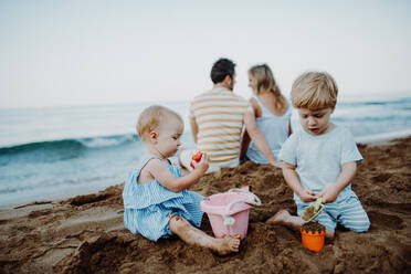 Kleinkinder mit Eltern spielen am Sandstrand im Familienurlaub. - HPIF23783