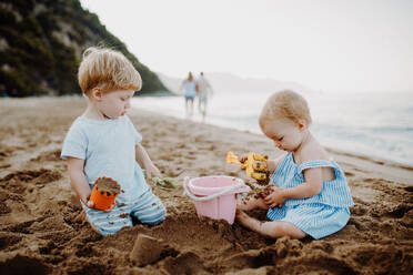 Zwei Kleinkinder spielen im Sommerurlaub mit der Familie am Sandstrand. - HPIF23784