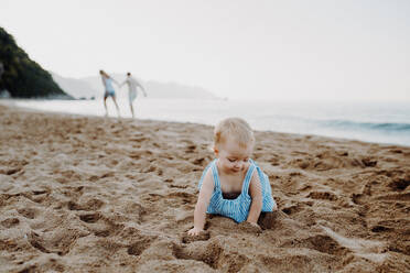Ein kleines Mädchen spielt im Sand am Strand im Sommerurlaub. - HPIF23787