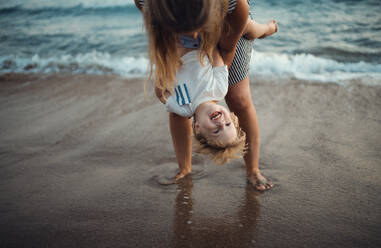 Eine junge Mutter mit einem Kleinkind am Strand im Sommerurlaub, die Spaß haben. - HPIF23840