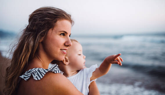 Eine Nahaufnahme einer jungen Mutter mit einem Kleinkind am Strand im Sommerurlaub. - HPIF23849