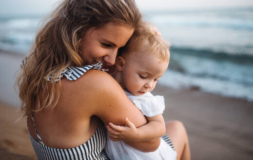 Eine Nahaufnahme einer jungen Mutter mit einem Kleinkind am Strand im Sommerurlaub. - HPIF23852