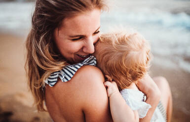 A close-up of young mother with a toddler girl on beach on summer holiday. - HPIF23853