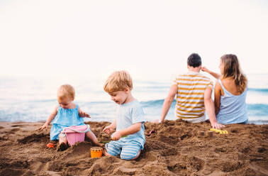 Kleinkinder mit Eltern spielen am Sandstrand im Familienurlaub. - HPIF23865