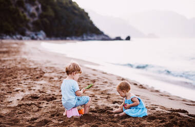Zwei Kleinkinder spielen im Sommerurlaub mit der Familie am Sandstrand. - HPIF23868