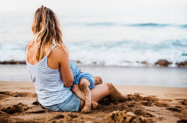 Eine junge Mutter stillt ihre kleine Tochter am Strand im Sommerurlaub. - HPIF23878