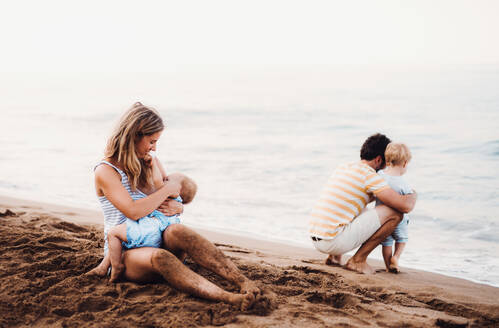 Eine junge Familie mit zwei Kleinkindern am Strand im Sommerurlaub. - HPIF23883