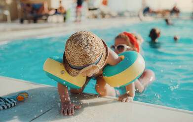 A happy small toddler boy with armbands and his mother swimming in water on summer holiday. - HPIF23931