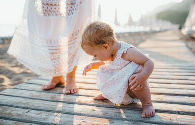 Ein Mittelteil der jungen Mutter mit einem Kleinkind Mädchen am Strand im Sommerurlaub. - HPIF23937